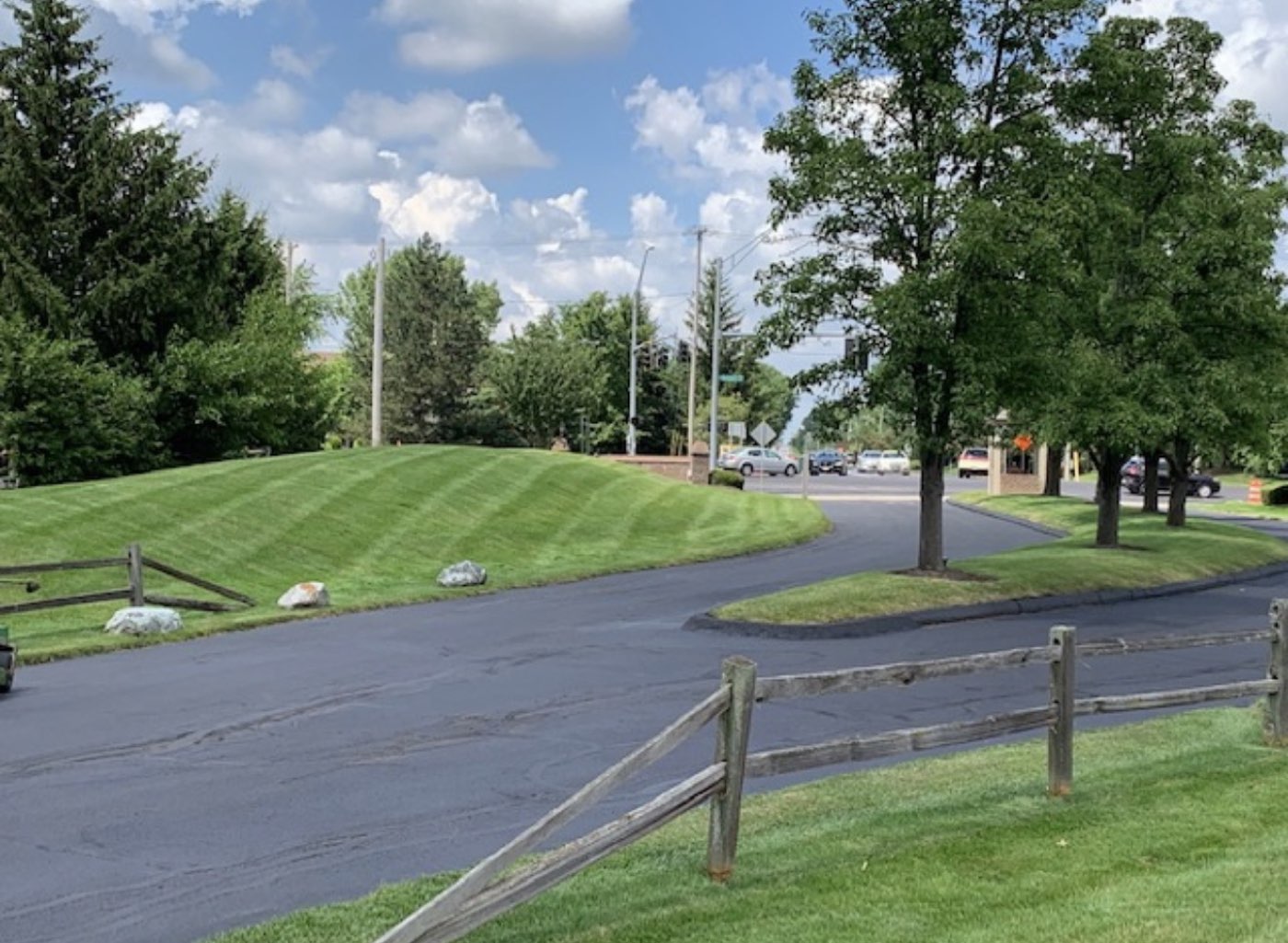 Freshly cut lawn on a sloped commercial property beside a parking lot drive